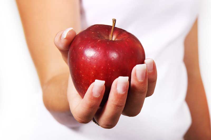 Photo of hand holding an apple.