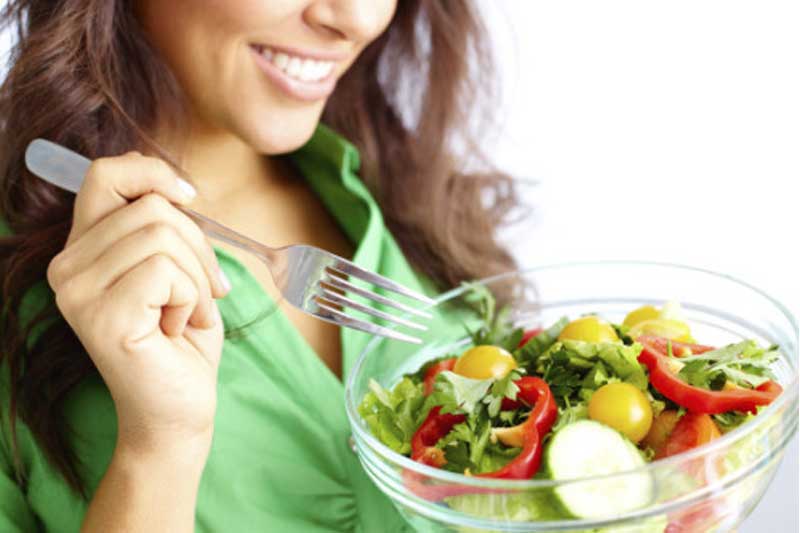 Photo of woman in green blouse eating a salad.