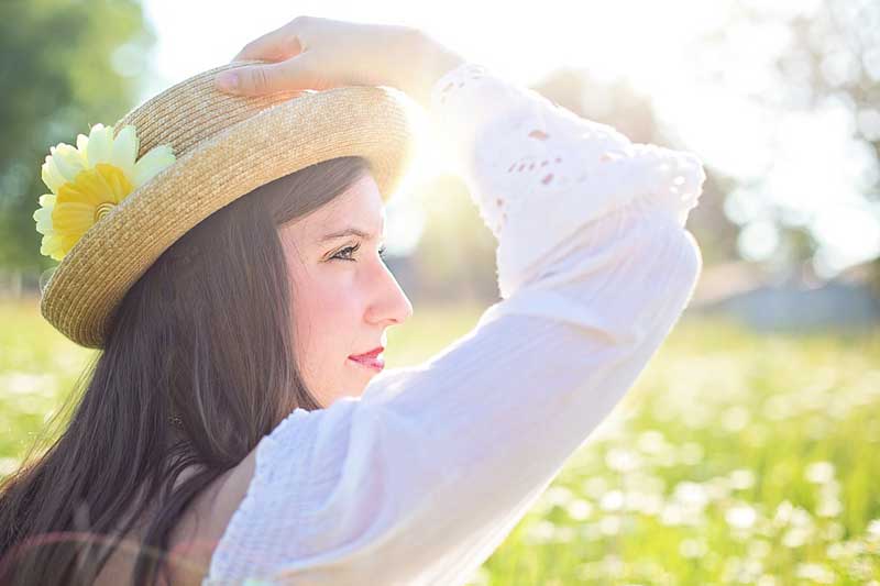 Photo of woman in a field wearing a hat.